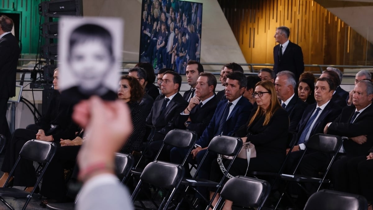 Un familiar alza la foto de un fallecido ante las autoridades poco antes del comienzo del funeral.
