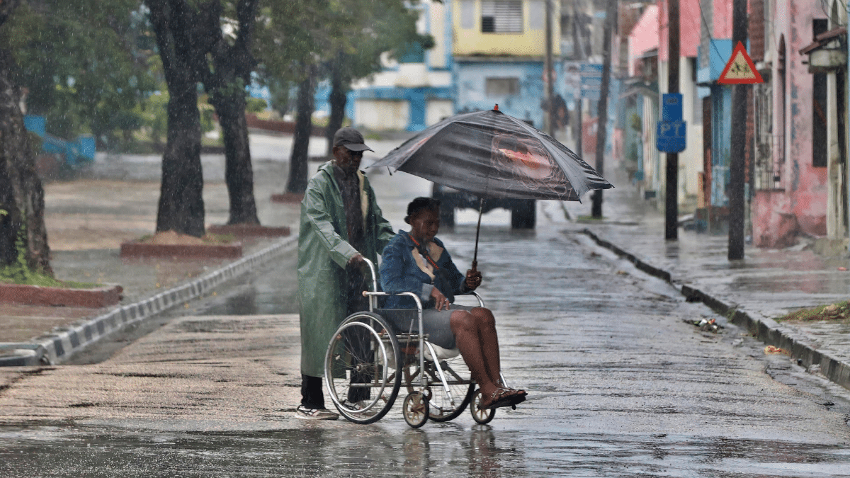Dos personas bajo la lluvia este martes en Santiago de Cuba, antes de la llegada de Melissa.
