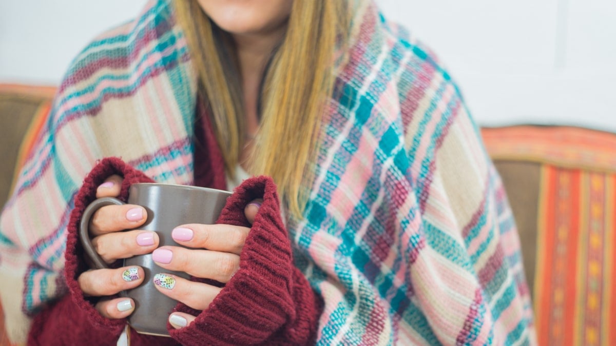 Chica con frío tomando una bebida caliente