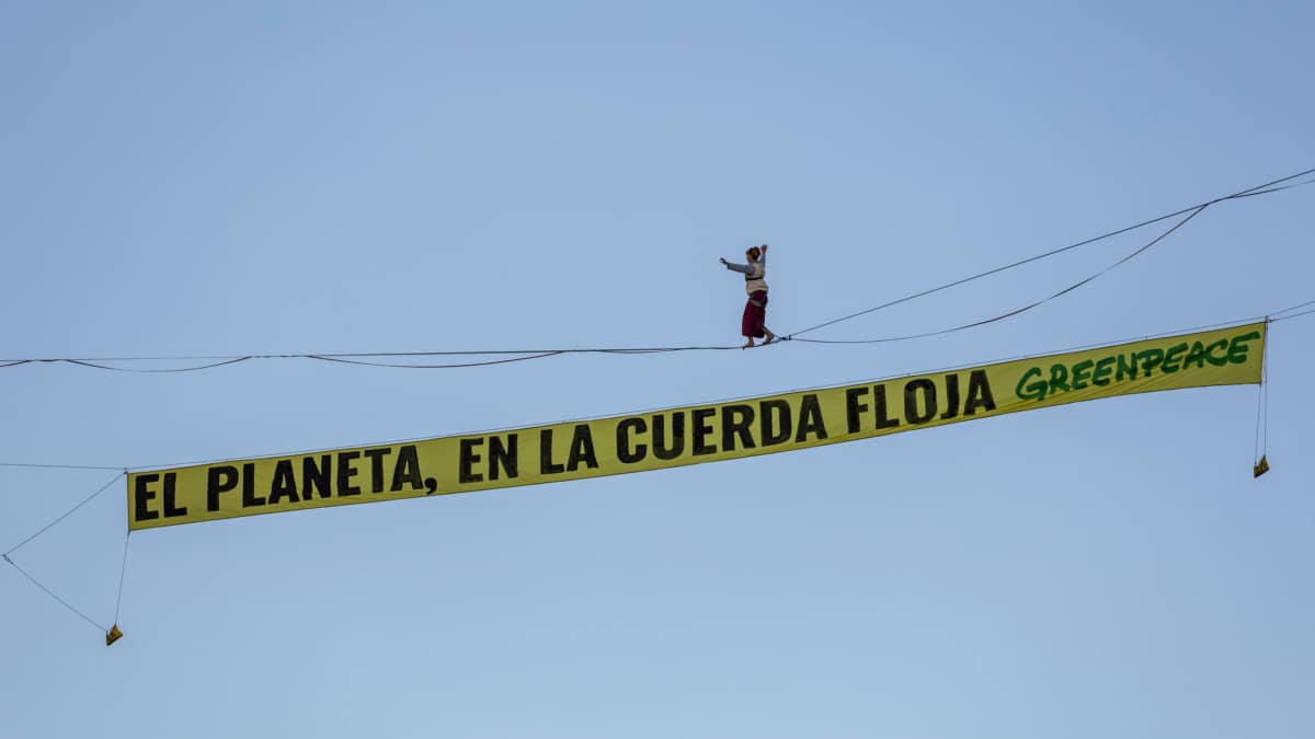 Una activista de Greenpeace camina sobre una cuerda a 30 metros en Madrid para denunciar la inacción climática
