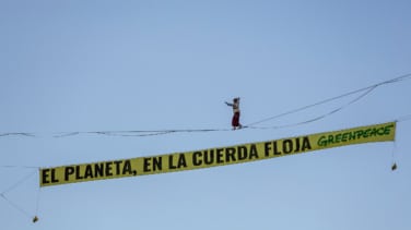 Una activista de Greenpeace camina sobre una cuerda a 30 metros en Madrid en el inicio de la COP30