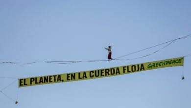 Una activista de Greenpeace camina sobre una cuerda a 30 metros en Madrid en el inicio de la COP30