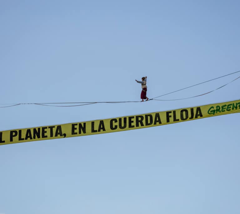 Una activista de Greenpeace camina sobre una cuerda a 30 metros en Madrid en el inicio de la COP30