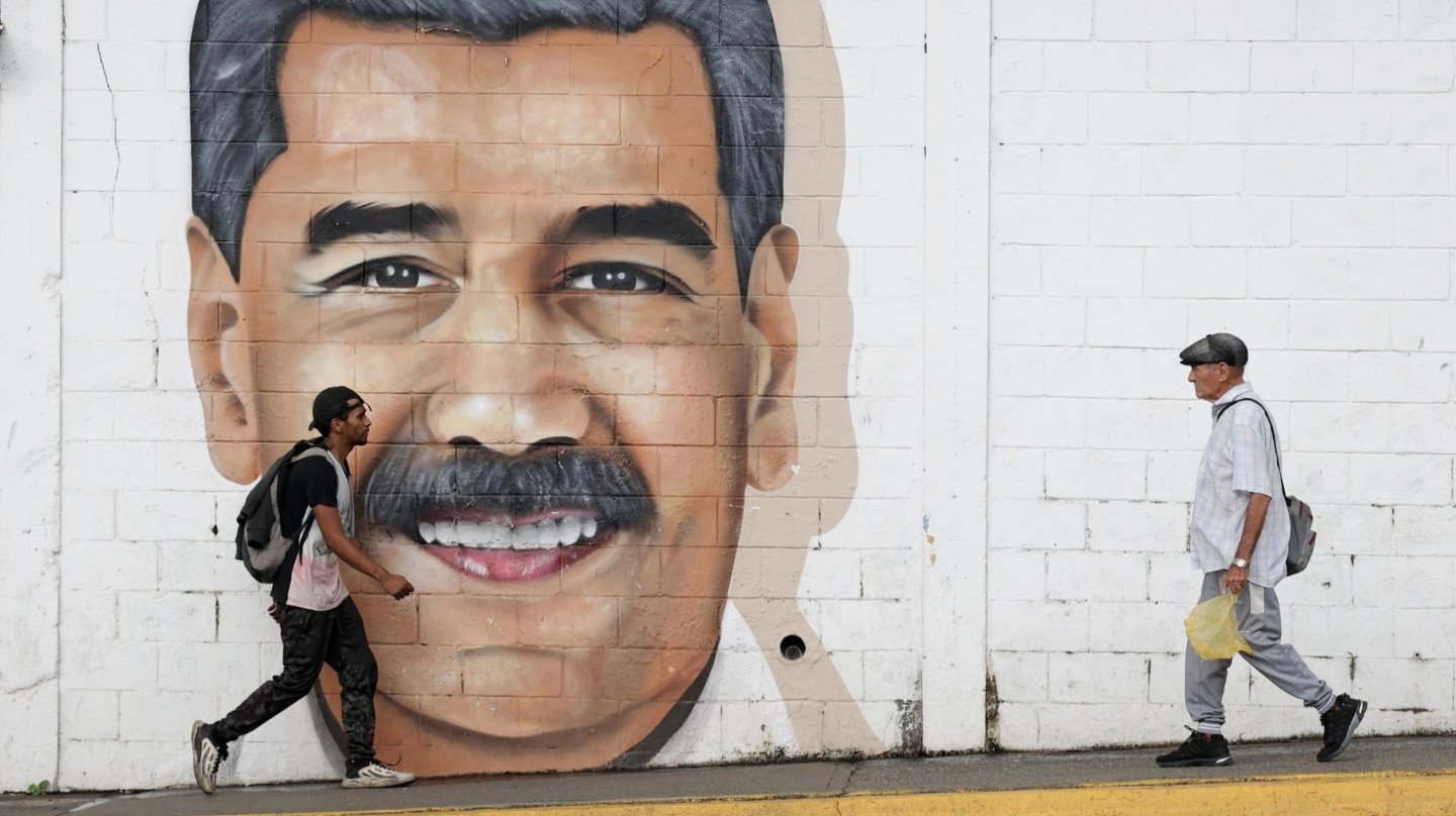 Personas caminan frente a un mural en Caracas