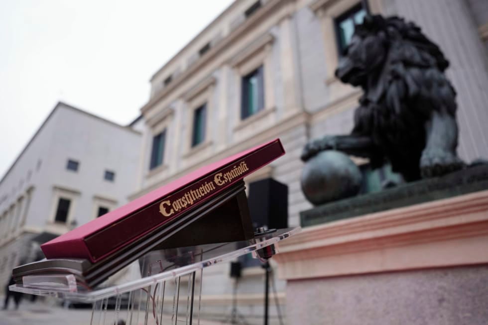 MADRID, 06/12/2025.- Ejemplar de la Constitución Española colocado ante los leones que custodian la entrada principal del Congreso de los Diputados antes del acto institucional por el Día de la Constitución, al que asistirán el presidente del Gobierno, Pedro Sánchez, y el líder de la oposición, Alberto Núñez Feijóo, entre otros dirigentes políticos, en una jornada marcada este año por una profunda división política, con la crispación en máximos y en medio de un ambiente electoral por el arranque de la campaña de las elecciones en Extremadura. EFE/Borja Sánchez-Trillo
