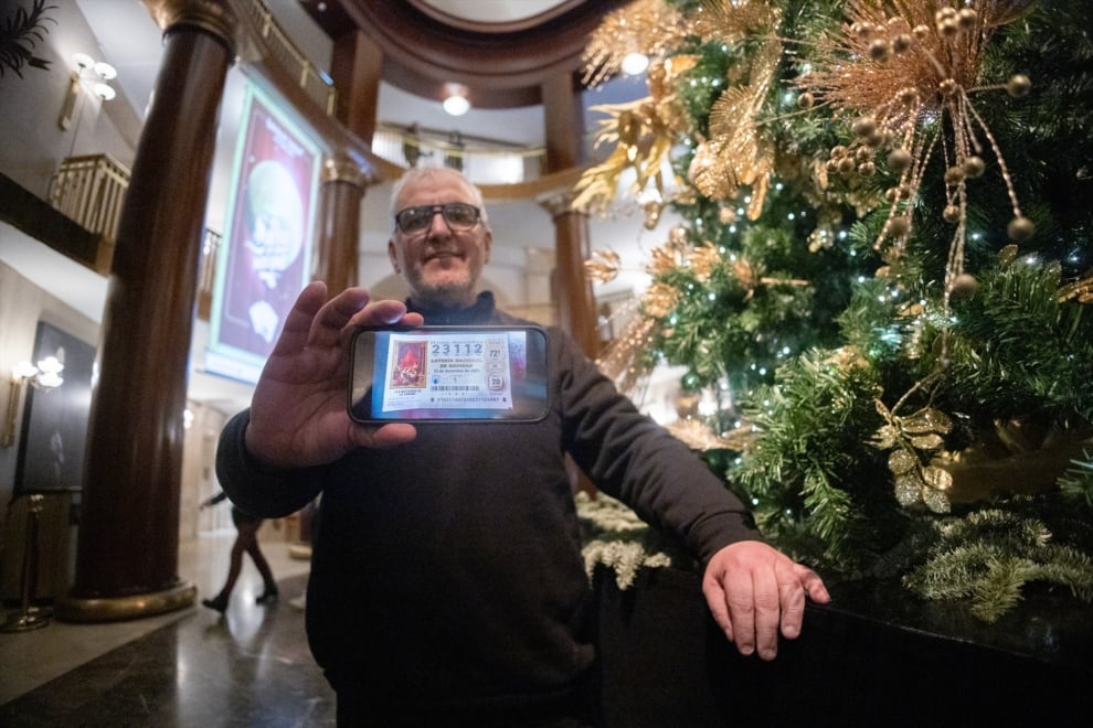Un agraciado con un Quinto Premio posa para Europa Press durante la celebración del Sorteo Extraordinario de la Lotería de Navidad 2025, en el Teatro Real, a 22 de diciembre de 2025, en Madrid (España). El Sorteo Extraordinario de la Lotería de Navidad de 2025 consta de 198 series y cada serie tiene 100.000 billetes. El total de la emisión asciende a 3.960 millones de euros y se destina a premios (70% de la emisión) 2.772 millones de euros. Cada serie distribuye en premios 14 millones de euros y en total se reparten 30.301.920 premios durante un sorteo que tiene una duración aproximada de cuatro horas.
Eduardo Parra / Europa Press
22/12/2025
