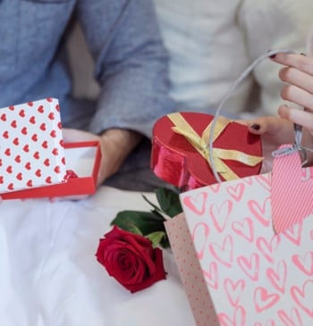 Pareja con regalos sentados en la cama
