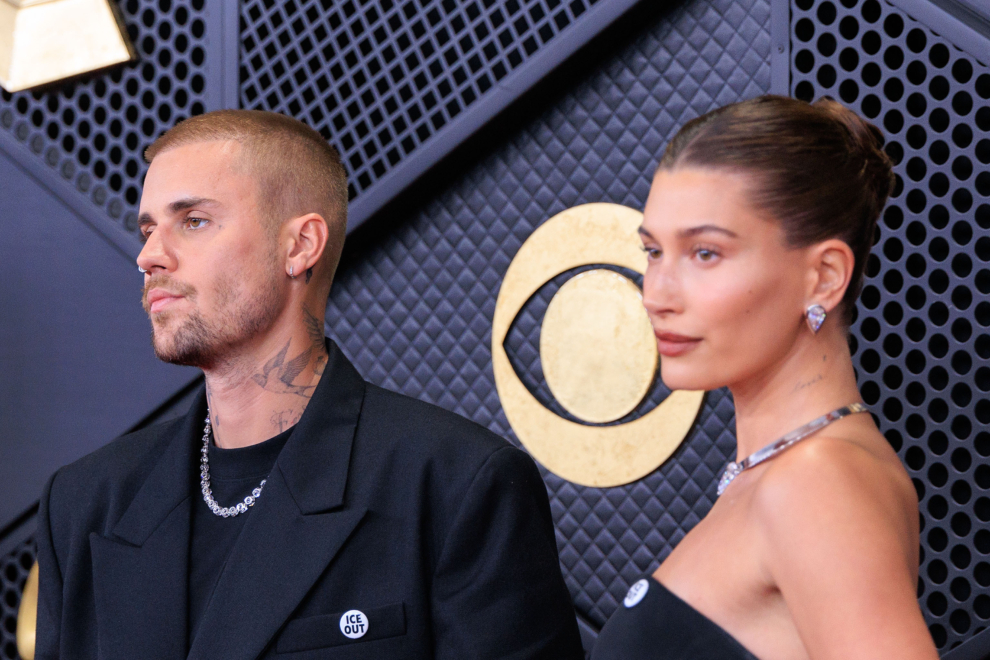 Justin Bieber junto a Hailey Bieber con el pin "ICE Out" en la alfombra roja de los Grammy 2026