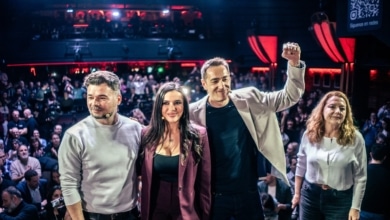 Carteles a favor de Podemos entre el público en el coloquio de Rufián con Delgado