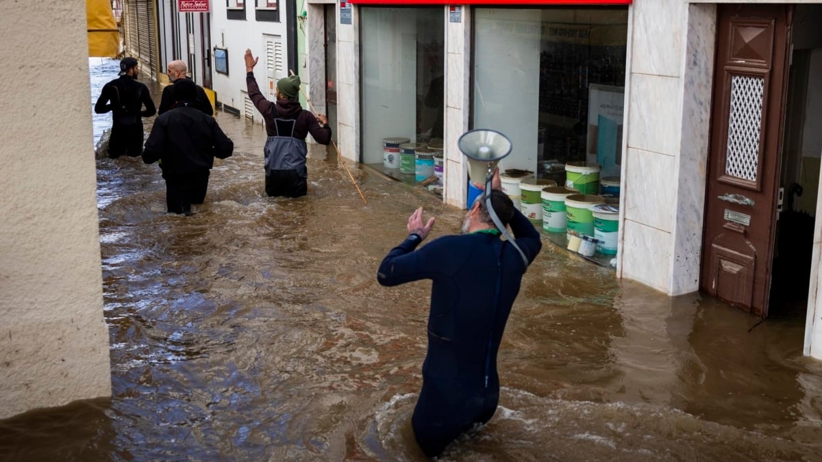 Varios voluntarios pasan por una zona inundada en Alcacer do Sal, Setúbal.