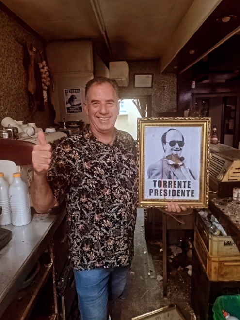 Imagen de Benito, dueño del Bar Benito con el cartel de 'Torrente Presidente'