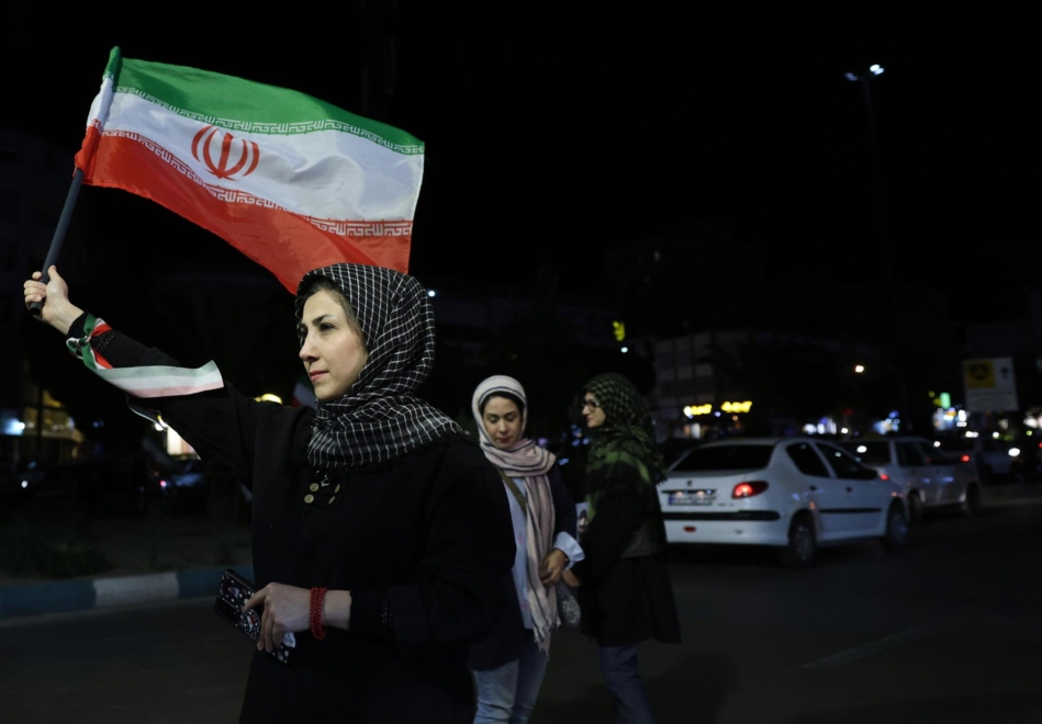 Una mujer ondea la bandera iraní por las calles de Teherán
