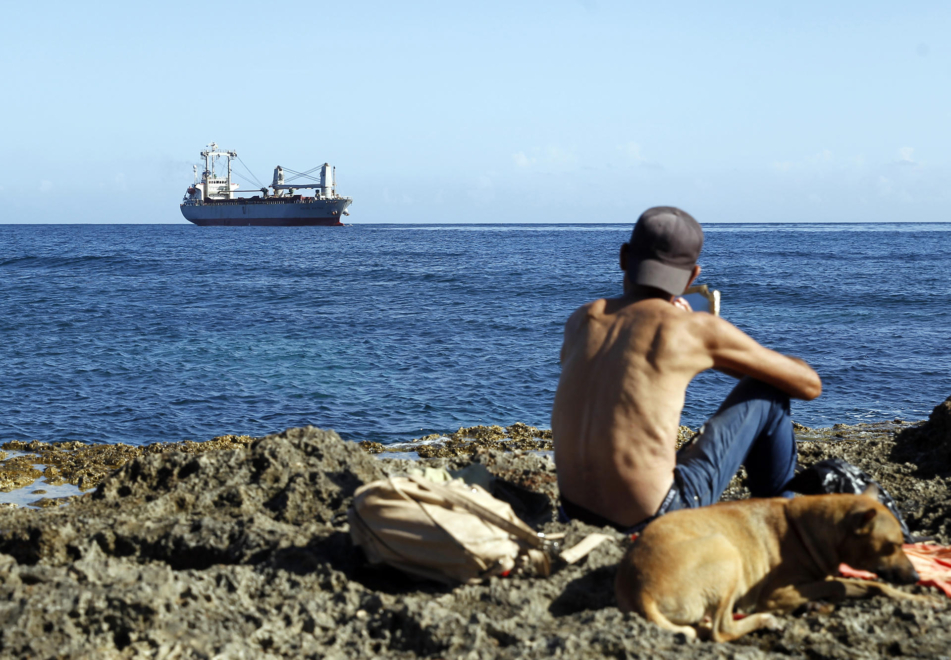 Un joven observa la llegada de un barco con ayuda humanitaria al puerto de La Habana