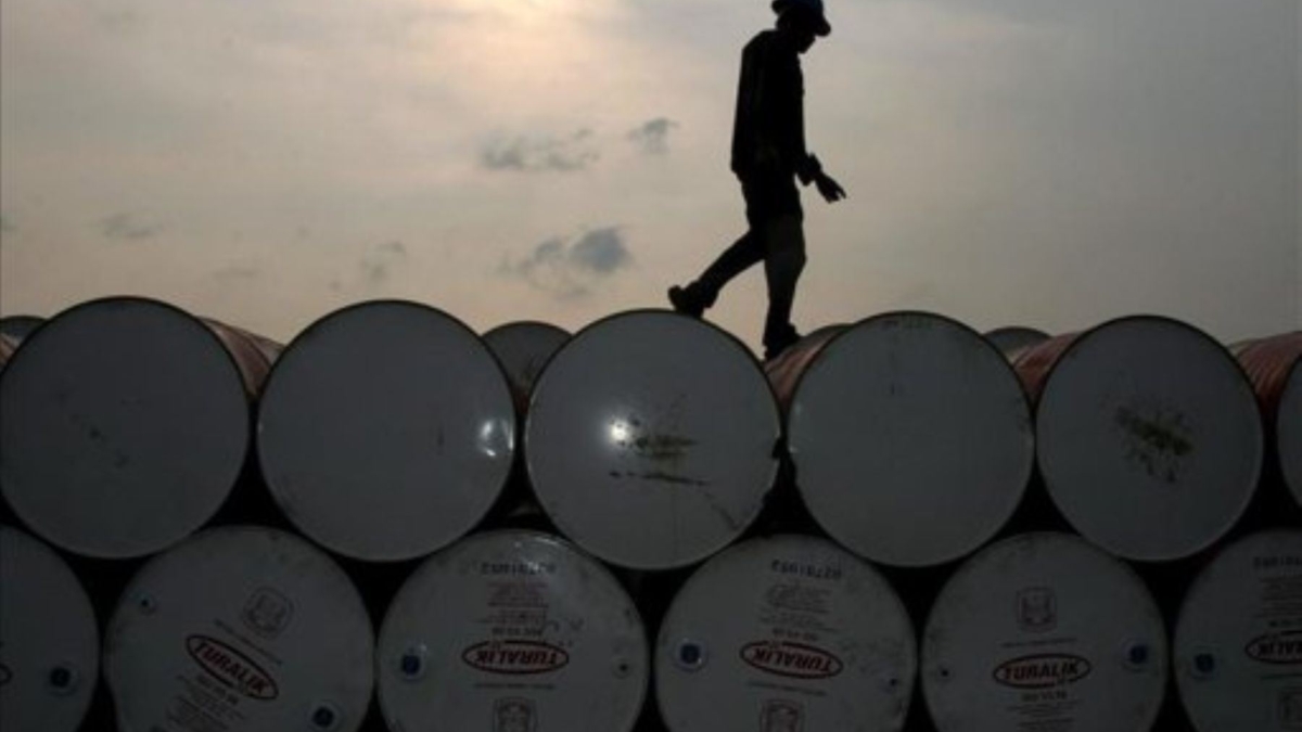 Un hombre camina sobre barriles de petróleo.