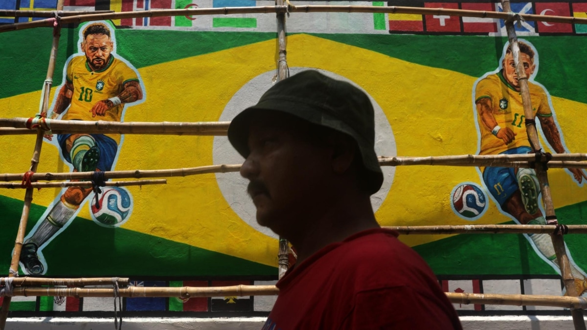 Un hombre pasa cerca de un mural con futbolistas brasileños en Kolkata, India.