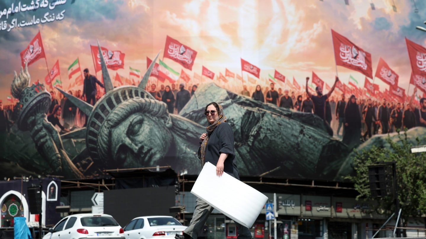 Una mujer iraní camina junto a una valla publicitaria antiestadounidense en Teherán.