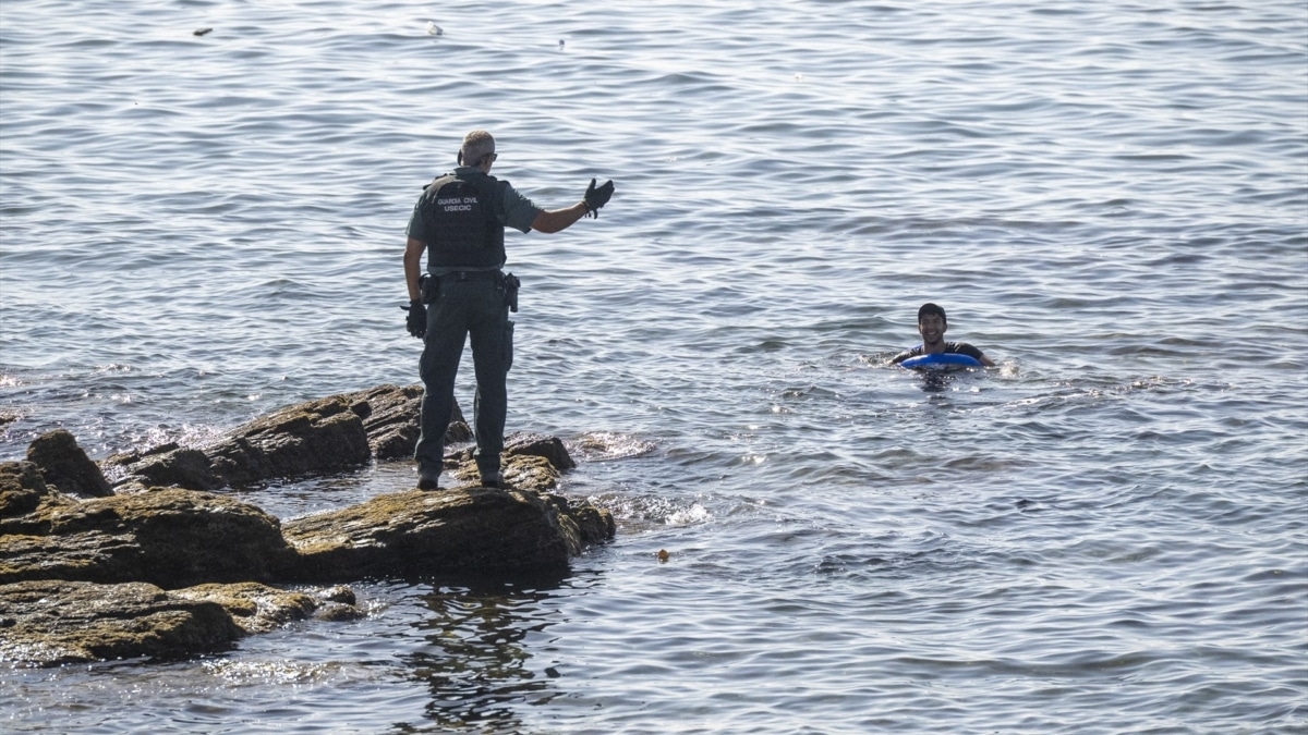 Un guardia civil avisa a una persona que nada en el mar