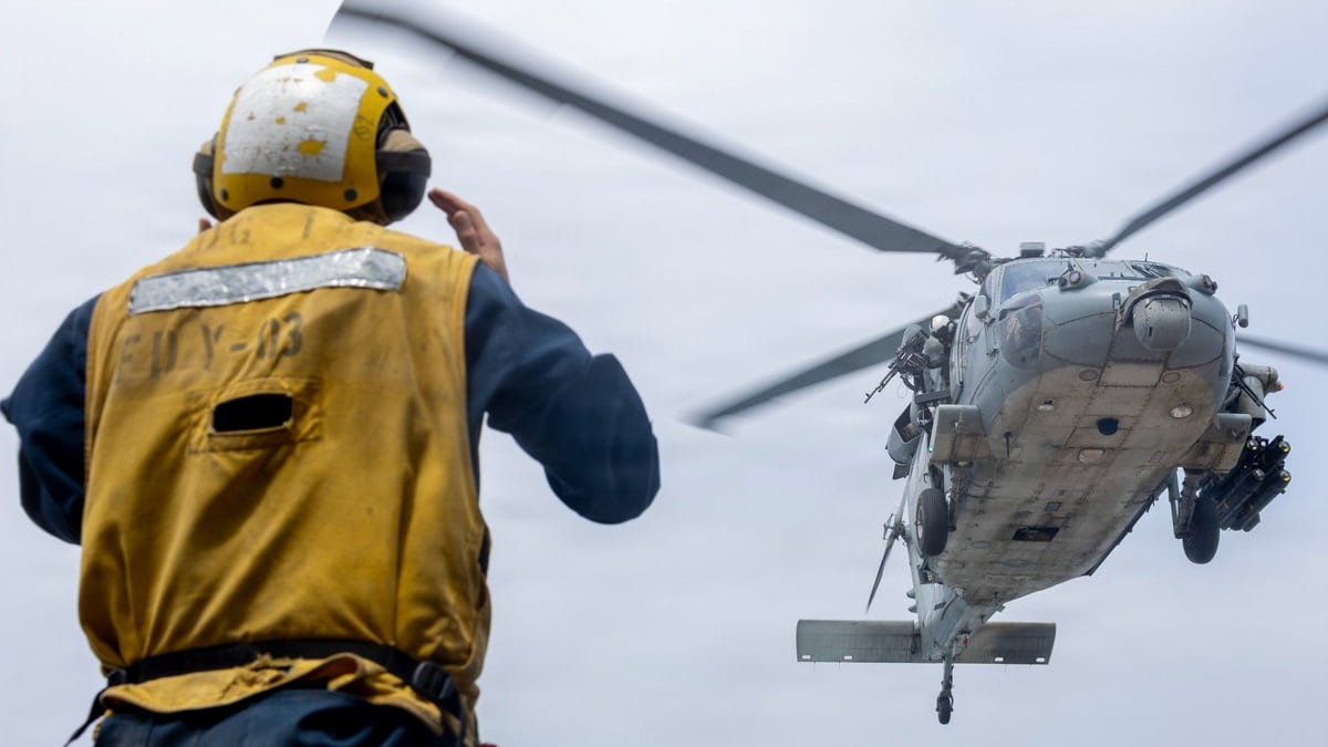 Un militar de EEUU da indicaciones a un helicóptero Hawk a bordo del USS Delbert D Black en operación de refuerzo del bloqueo contra Irán