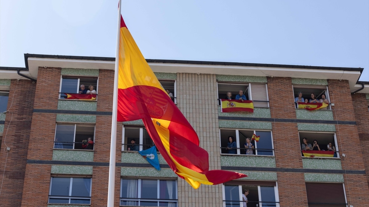 Varios vecinos en los balcones con banderas de España durante el desfile militar con motivo del día de las fuerzas armadas