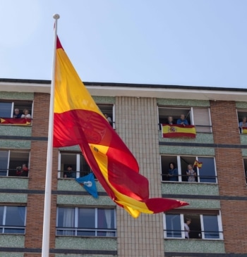 Varios vecinos en los balcones con banderas de España durante el desfile militar con motivo del día de las fuerzas armadas