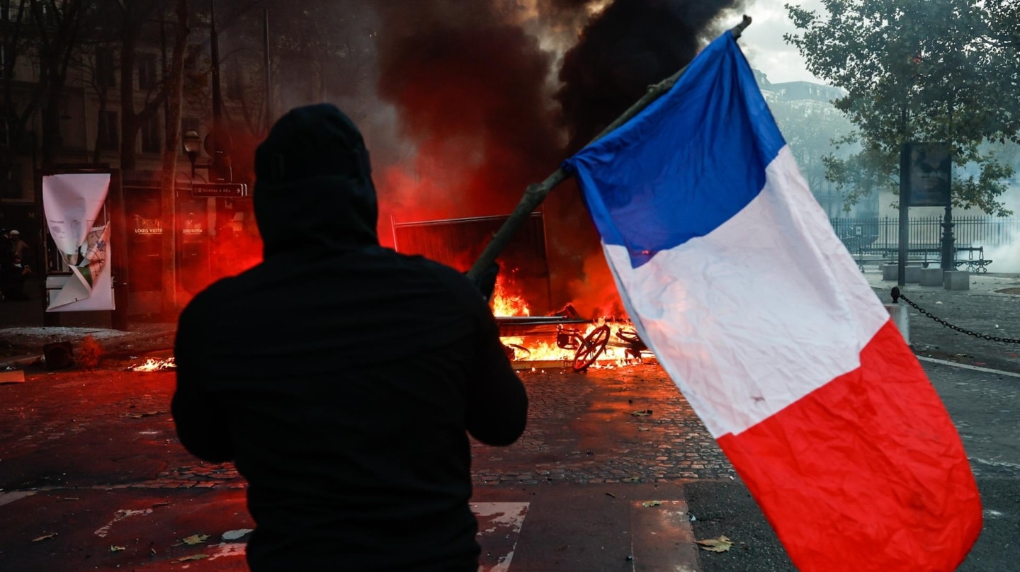 Un manifestante porta una bandera de Francia frente a la policía en la Place de la Madeleine de París.