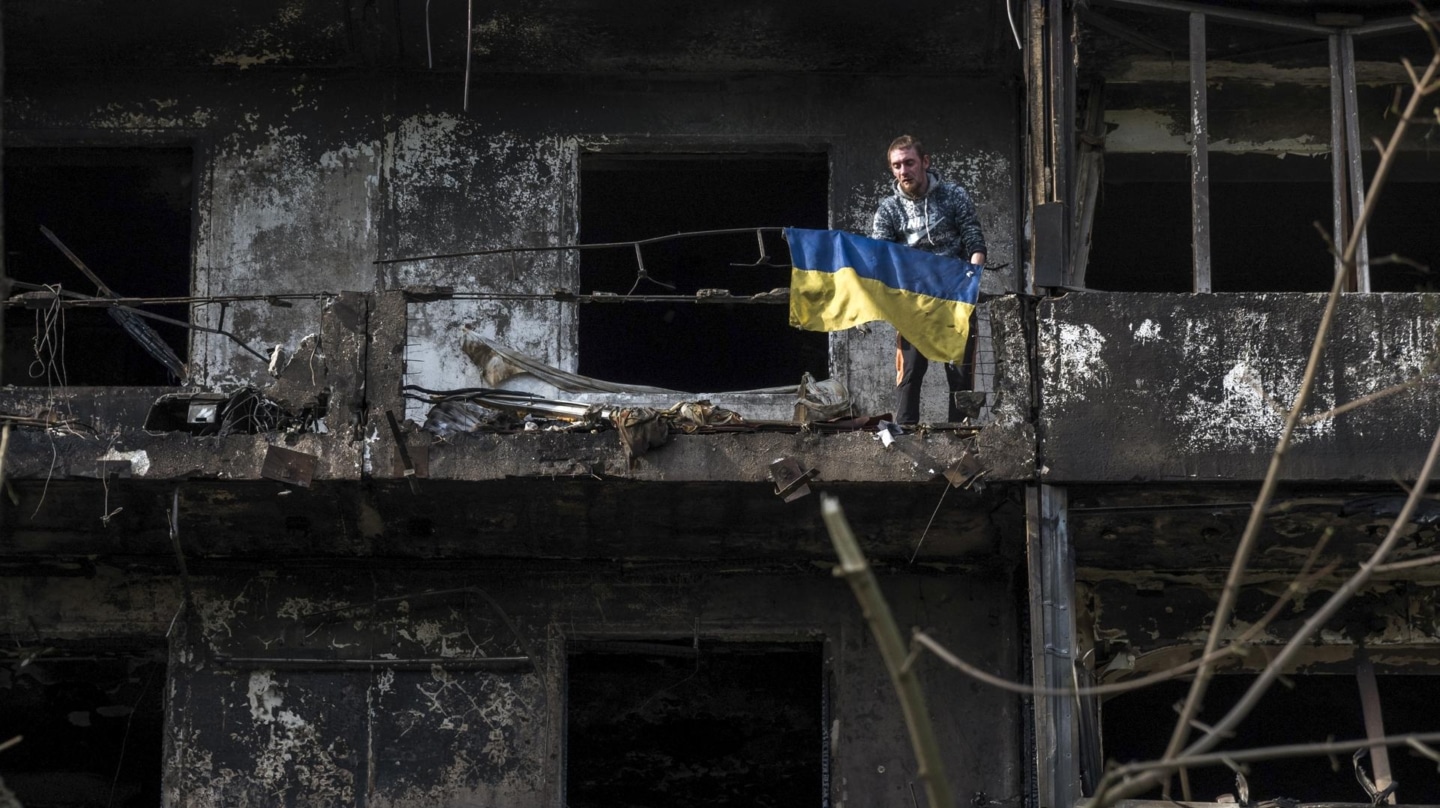 Un hombre sostiene una bandera en los restos de un edificio residencial donde ha caído un misil ruso en Kiev.