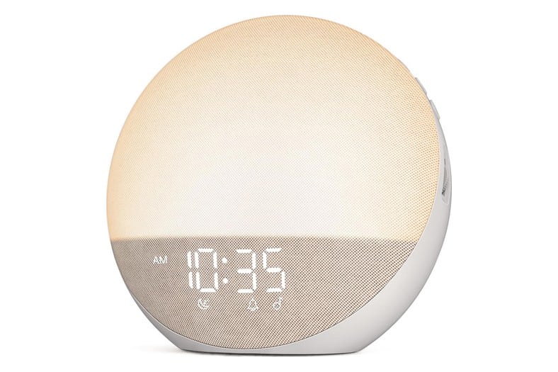 Despertador redondo NingPeak con simulación de amanecer, acabado de tela beige arena y luz cálida encendida