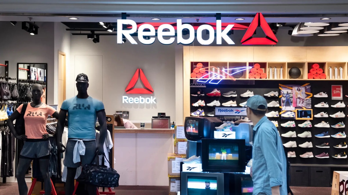 Tienda Reebok: maniquíes con ropa azul y naranja, zapatillas en estantes, hombre con gorra